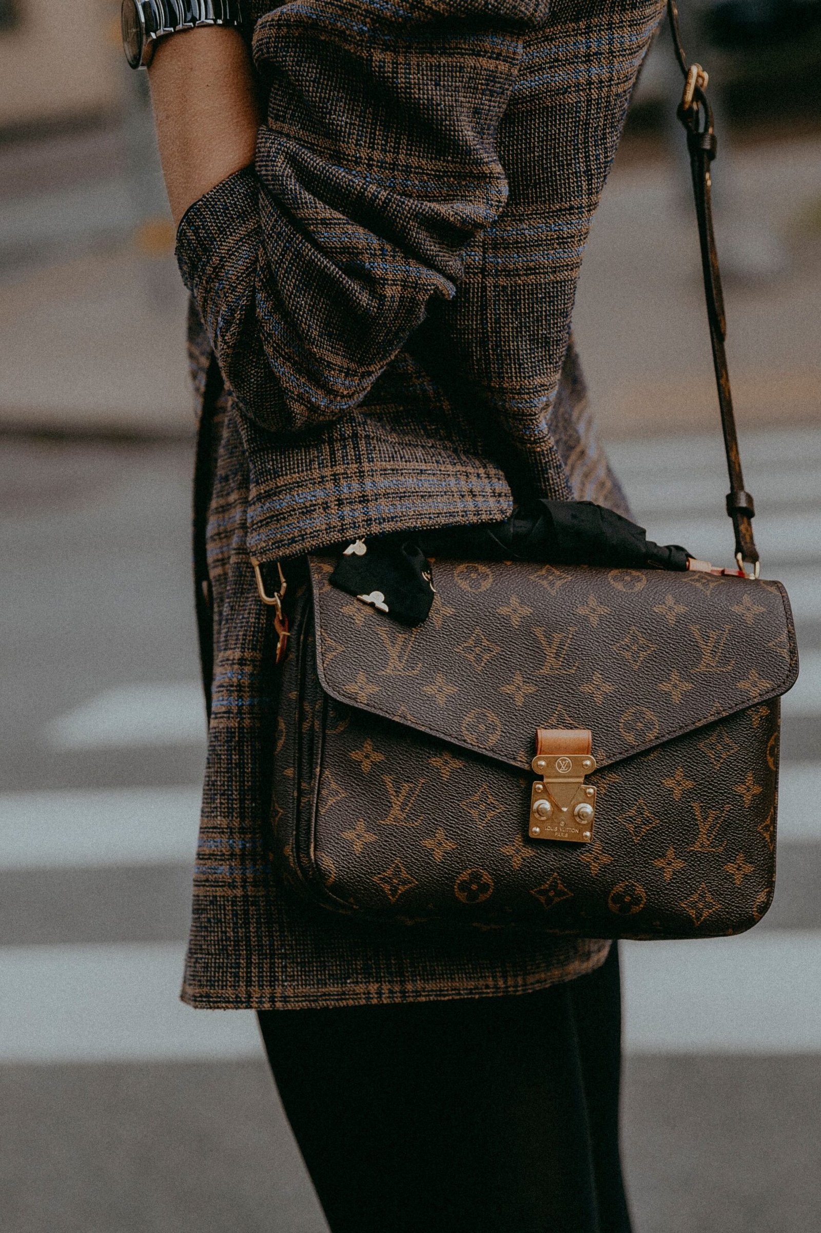 Fashionable woman with a designer bag, showcasing modern urban style in a street setting.